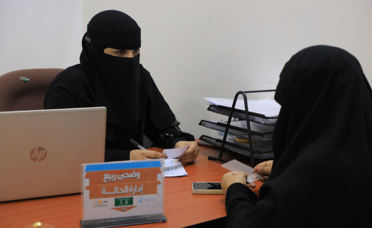  امرأتان ترتديان النقاب الأسود تتحدثان عبر مكتب به كمبيوتر محمول ودرج ملفات]